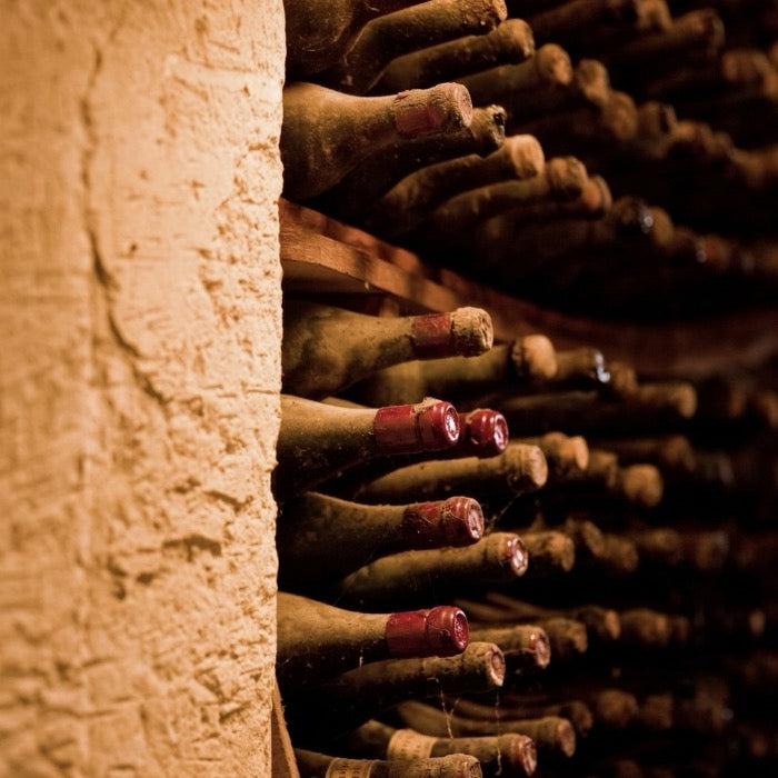 Vu sur une cave en pierre qui accumule des bouteilles de vin à l'horizontale avec des goulots en cire rouge
