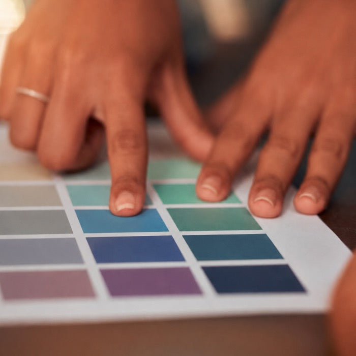 sur une feuille blanche avec plein de carré de différente couleurs, deux mains sont en cours de selection d'une couleur. 