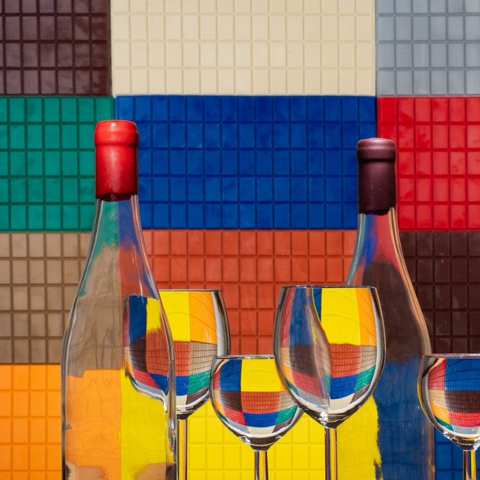 Dans le fond, se tiennent de nombreuses plaques de cire de couleurs différentes et, au premier plan, deux nougats cirés en rouge et du liège de vin avec 4 verres transparents. 