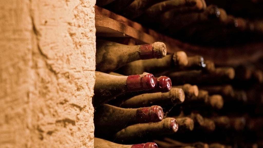 Vu sur une cave en pierre qui accumule des bouteilles de vin à l'horizontale avec des goulots en cire rouge