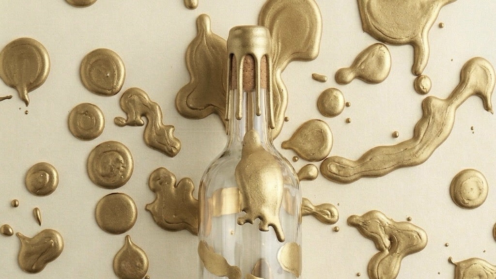 Bouteille en verre transparente avec de la cire dorée dure brillante sur le goulot et des tache en fond de cire dorée