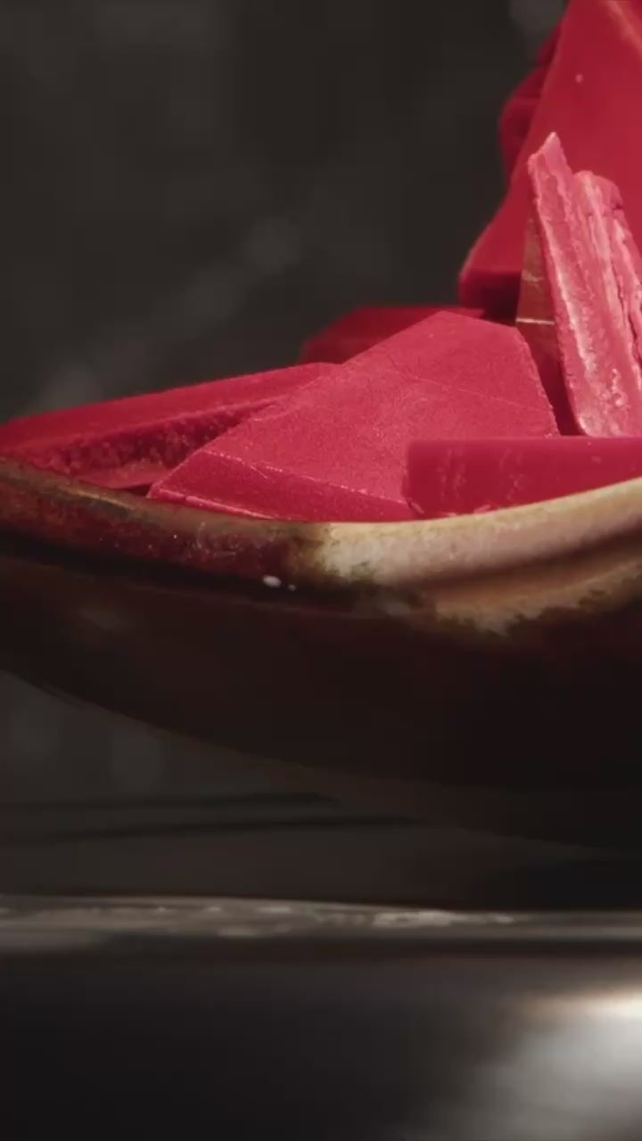 des carrées de cire rouge dans un pot recoivent de la cire rouge fondu par le dessus
