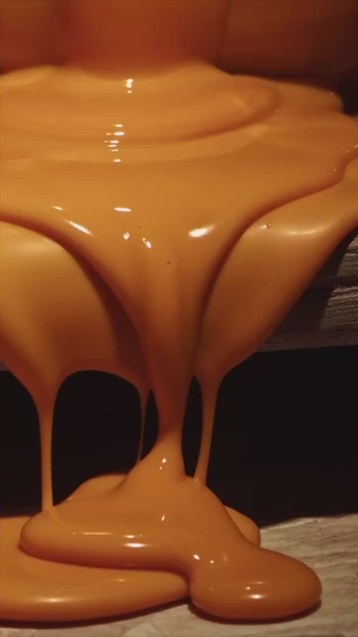 De la cire orange semblable à du caramel s'écoule lentement sur une table en escalier