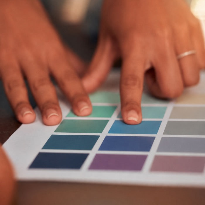 une main en train de chercher une couleur parmis un nuancier